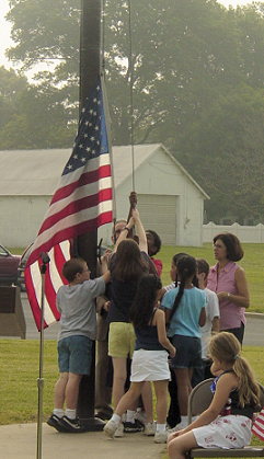 Principal Loretta Savidge and students raise the American flag on the Samuel Mickle School flagpole